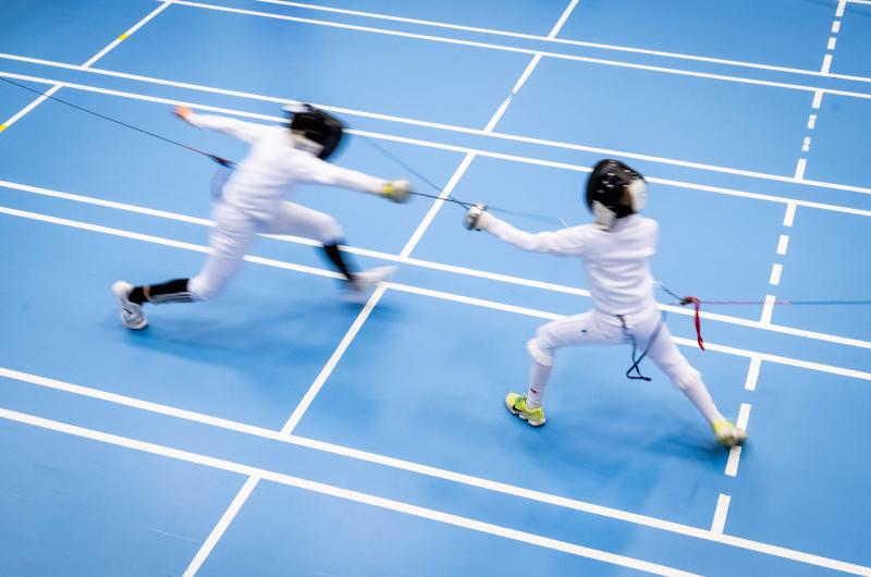 Unga fäktare i aktion under tävling.