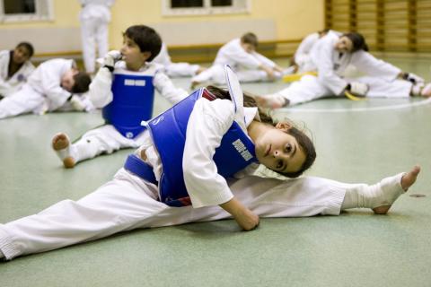 Flicka stretchar under träning i taekwondo.
