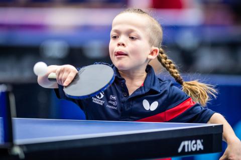 Flicka med lång fläta ska just slå en backhand i bordtennis.