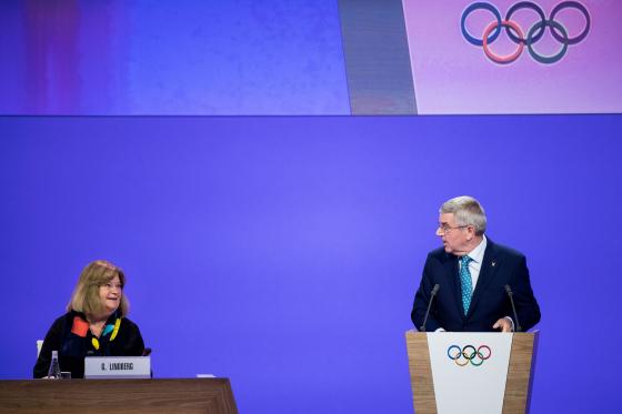 En kvinna och en man från IOK på ett podium
