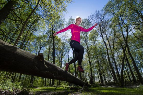 Kvinna springer över en stock i skogen
